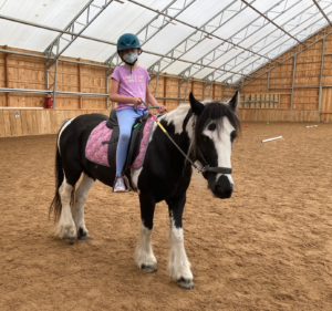 Neve riding a horse named Ruby at Horse SenseAbility in Sherborn, MA, and supported by The Genesis Foundation for Children