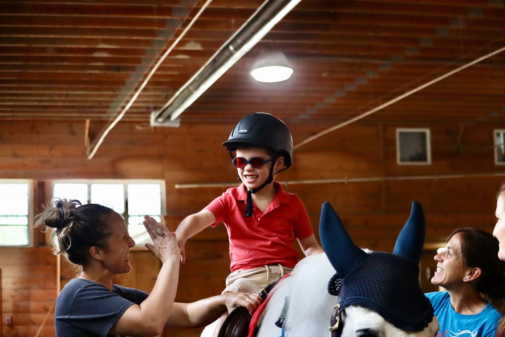 Dillion high fiving his instructor on a horse